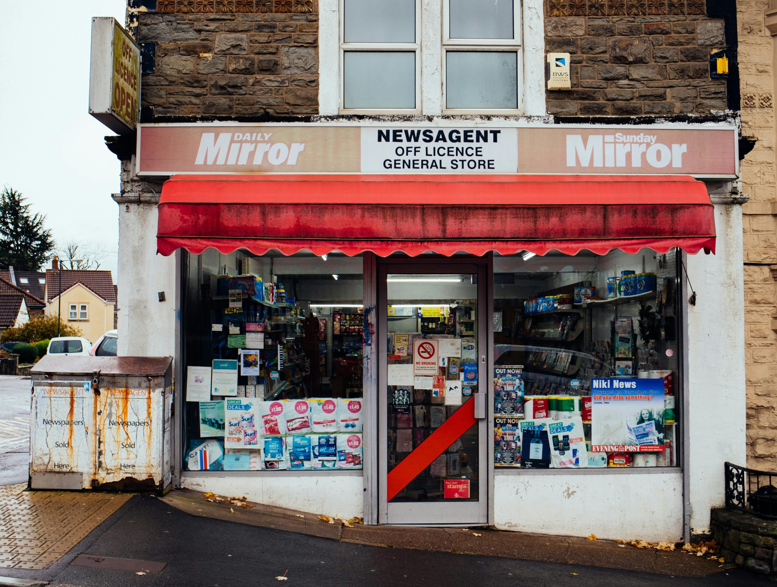 Classic urban newsagent storefront with vibrant signage and red awning, perfect for illustrating local retail commerce.